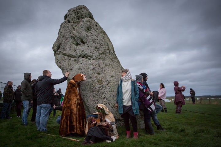 People gather around a stone during the winter solstice ceremony at Stonehenge on December 22, 2015.