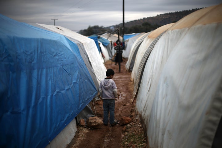 <strong>A child walks between tents in a tent camp at Qah town of Idlib on December 16</strong>