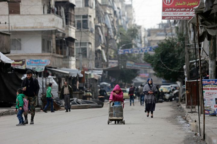 A Syrian girl pushes a cart loaded with cooking gas canisters, in Aleppo.