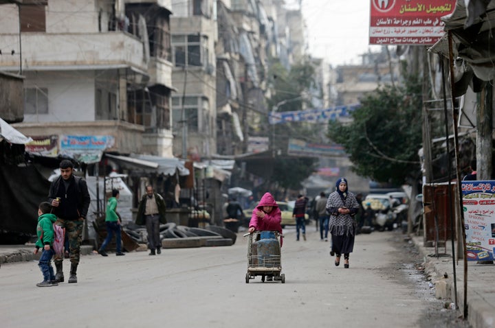 <strong>A Syrian girl pushes a cart loaded with cooking gas canisters, in Aleppo.</strong>