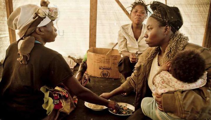 Displaced women in eastern Democratic Republic of the Congo eating together in a shared tent.