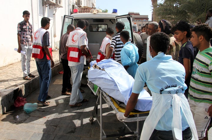 Yemeni medics transport a body into a hospital in Aden on December 18, 2016, after a suicide bomber targeted a crowd of soldi