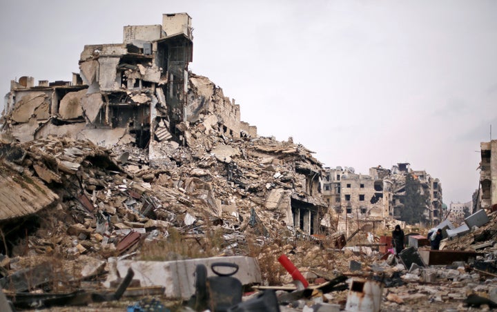 People carry belongings as they walk on the rubble of damaged buildings in the government controlled area of Aleppo, Syria De