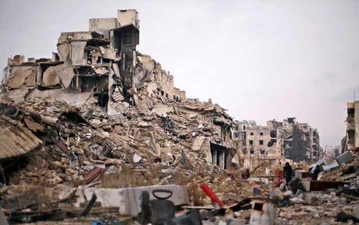 People carry belongings as they walk on the rubble of damaged buildings in the government controlled area of Aleppo, Syria December 17, 2016