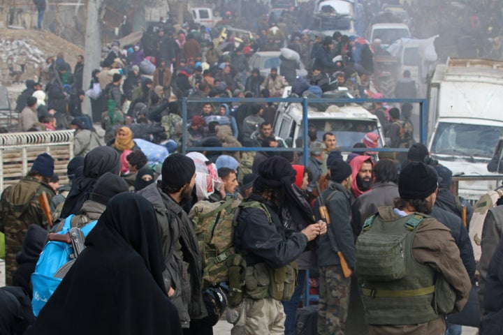 Rebel fighters and civilians gather as they wait to be evacuated from a rebel-held sector of eastern Aleppo, Syria.