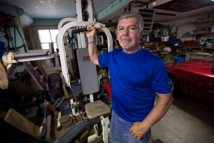 Mike Dennen, who was diagnosed with mesothelioma four years ago, in his garage in Bourne where he works out to keep fit. 