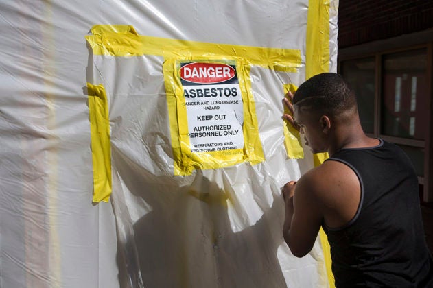 Using plastic and duct tape, a worker fabricates an asbestos containment barrier on a doorway of the Teaticket School in Falmouth, Mass.