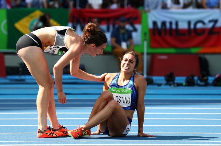 Abbey D'Agostino of the United States (R) is assisted by Nikki Hamblin of New Zealand after a collision during the Women's 5000m.
