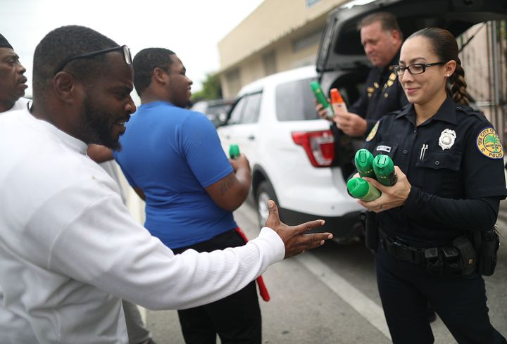 Miami police officers give out cans of insect repellent as they help people near the Miami Rescue Mission prevent mosquito bites that may infect them with the Zika virus on August 2, 2016 in Miami, Florida.