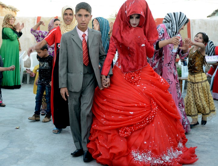 Hussein Younis Ali, 14 walks with his bride Nada Ali Hussein, 17, during the wedding party at his home in Tikrit, 150 km (93 miles) north of Baghdad, October 8, 2013. Boys and girls are married at an early age in Iraq's rural areas by local clerics who ignore Iraq's law that forbids under-aged marriages under the age of 16.