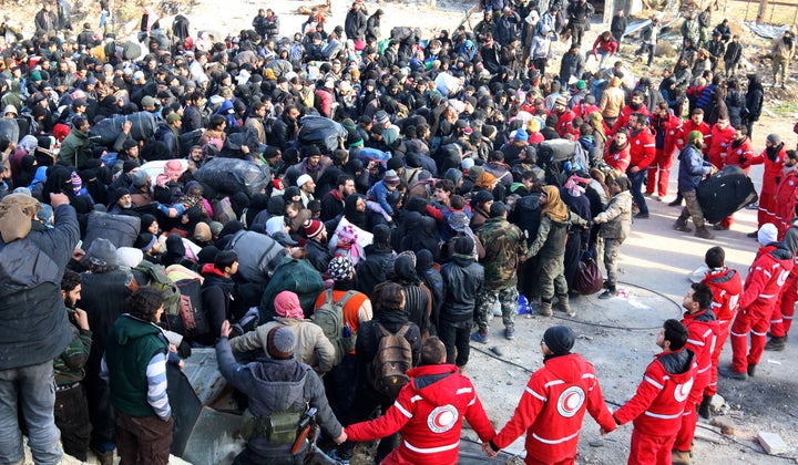 Red Crescent members hold hands while rebel fighters and civilians wait to be evacuated from a rebel-held sector of eastern Aleppo