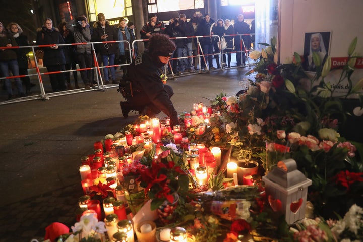 A policewoman places a candle on behalf of a mourner at a makeshift memorial on Dec. 20.