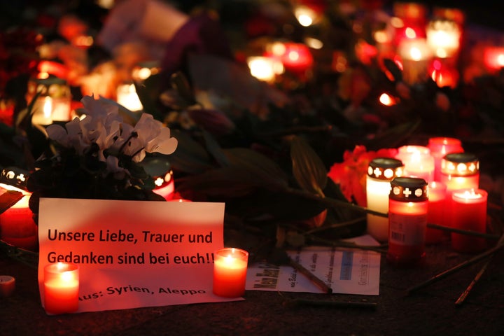 A paper reading "Our love, mourning and thoughts are with you" lies between candles on Dec. at a makeshift memorial for the victims.