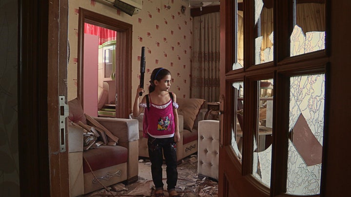 Farah emulates her father with a toy gun in their old Aleppo apartment.