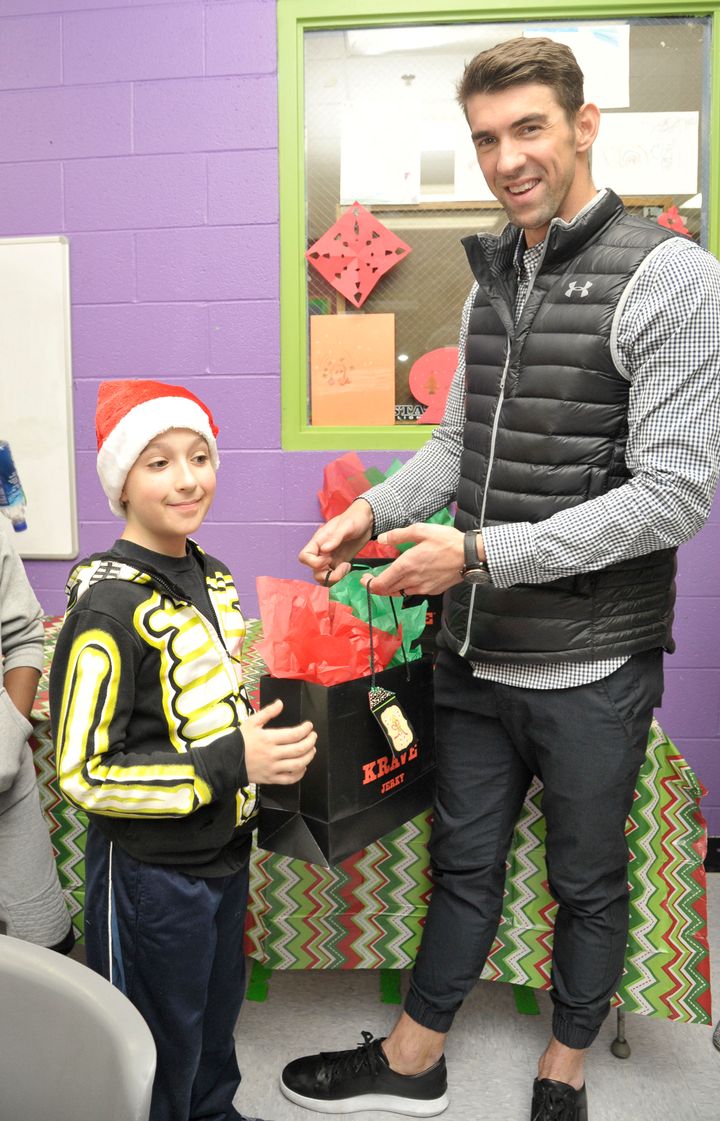 Michael Phelps hands out a gift bag during a Dec. 16 visit to the Boys & Girls Club.