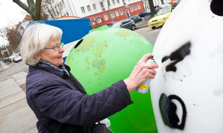 Irmela Mensah-Schramm spray paints over a Nazi symbol on a recycling bin in eastern Berlin's Lichtenberg district.