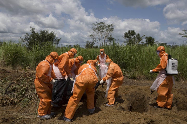 A burial team wearing protective clothes prepares an Ebola virus victim for interment, in Port Loko, Sierra Leone, September 27, 2014.