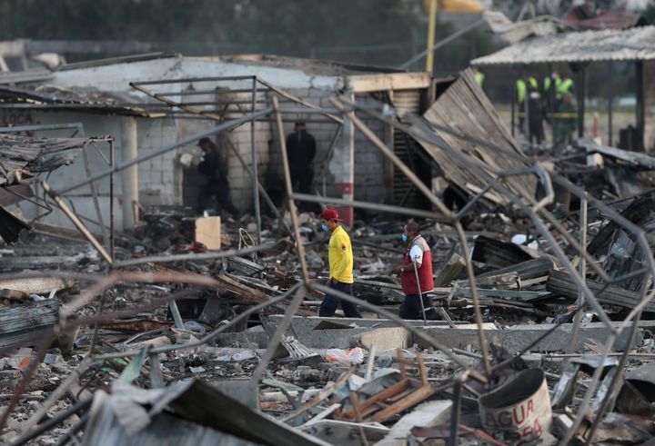 People walk amidst the remains of houses destroyed in the blast.