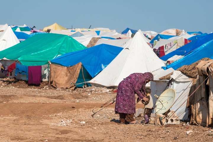 Atmeh, Syria: A Syrian woman and boy stand outside their shelter in the camp for displaced persons.