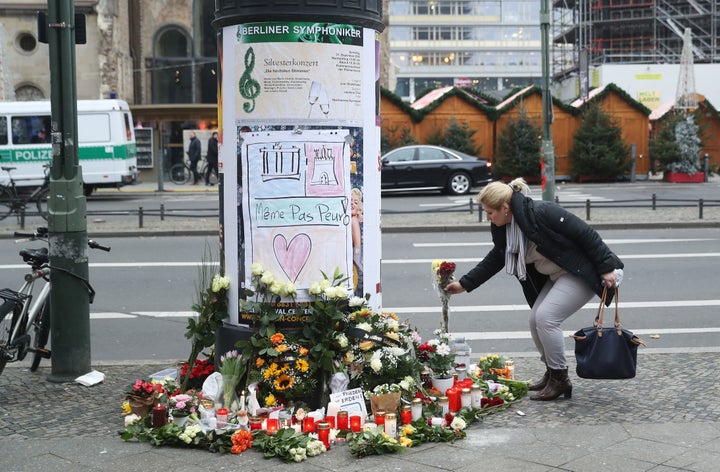 A woman lays flowers near where yesterday a lorry ploughed through a Christmas market in Berlin