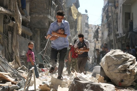 <p>Syrian men carrying babies make their way through the rubble of destroyed buildings following a reported airstrike on the rebel-held Salihin neighbourhood of Aleppo on Sept. 11, 2016</p>