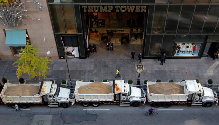 A cyclist rides by a row of sanitation trucks filled with sand acting as barricades along Fifth Avenue outside Republican presidential nominee Donald Trump's Trump Tower in Manhattan, New York, U.S., November 8, 2016.