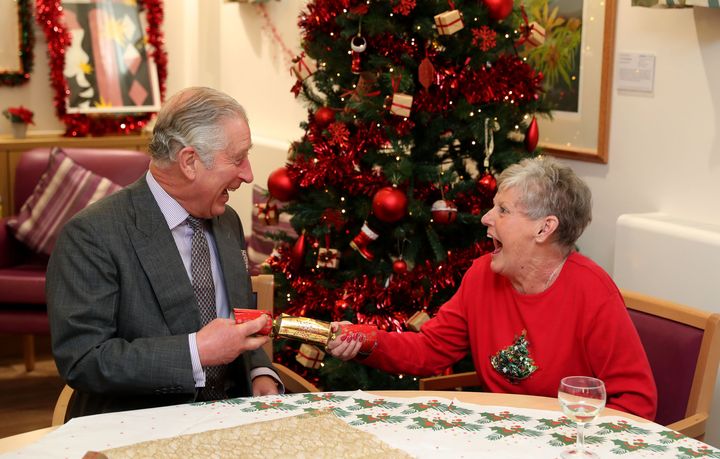 The Prince of Wales pulls a Christmas cracker with Barbara Stacey during a visit to the Sue Ryder Leckhampton Court Hospice near to Cheltenham in Gloucestershire.
