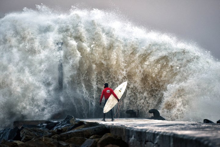 A huge wave crashes against Castlerock pier as professional surfer Al Mennie waits on a break in the swell on December 22, 2016 in Coleraine, Northern Ireland.