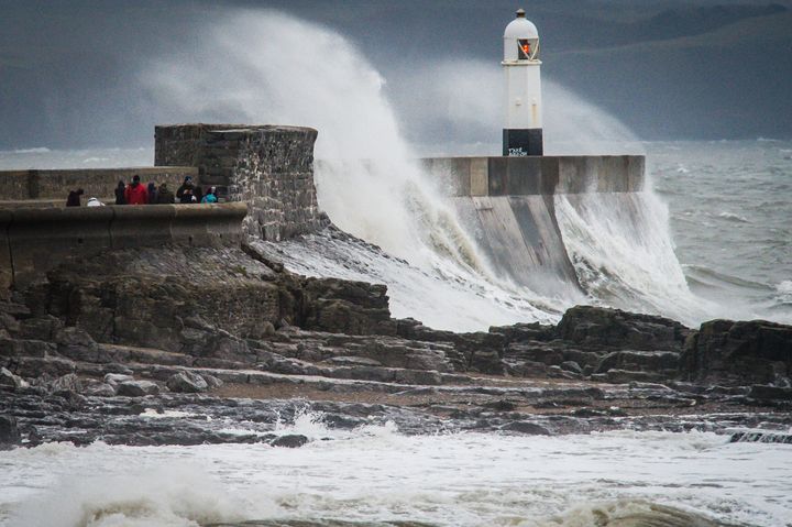 <strong>People watch waves crash over the harbour wall at Porthcawl, South Wales, as the UK braces for Storm Barbara - and Storm Conor </strong>