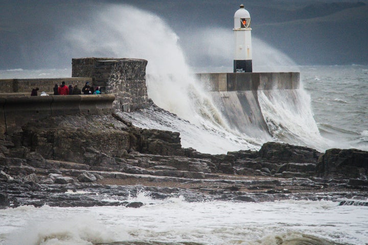 People watch waves crash over the harbour wall at Porthcawl, South Wales, as the UK braces for Storm Barbara - and Storm Conor 