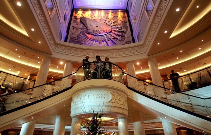 Passengers stand on a balcony above the Grand Lobby inside the Queen Mary 2 moored at Garden Island in Sydney February 20, 2007.