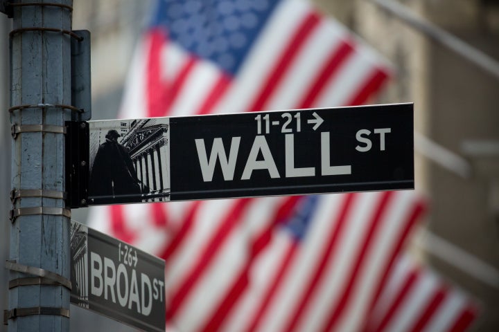 A Wall Street sign is displayed as American flags fly in front of the New York Stock Exchange (NYSE) in New York, U.S., on Monday, Nov. 21, 2016. (Photographer: Michael Nagle/Bloomberg via Getty Images)