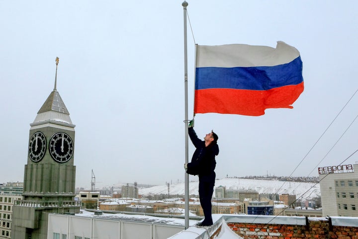 A worker lowers the Russian national flag to half-mast on a roof of Krasnoyarsk's administration building, as the country obs