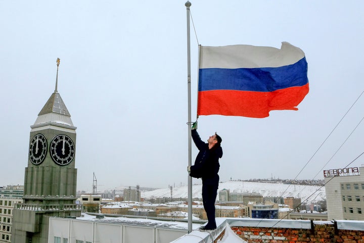 A worker lowers the Russian national flag to half-mast on a roof of Krasnoyarsk's administration building, as the country observes a day of mourning for victims of the Tu-154 plane which crashed into the Black Sea.