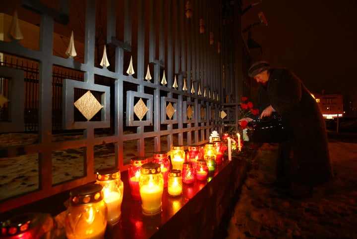 A woman lays flowers at the Russian embassy in Minsk, Belarus, in memory of passengers and crew members of Russian military T