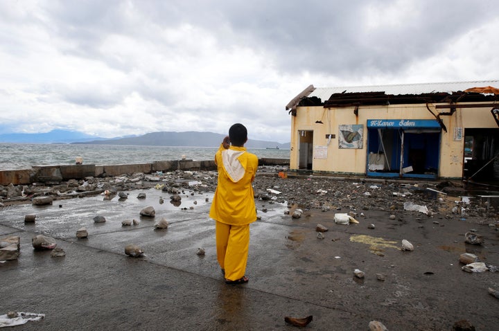 A port worker stands amidst debris swept from the sea at the height of Typhoon Nock Ten in Mabini, Batangas, in the Philippin