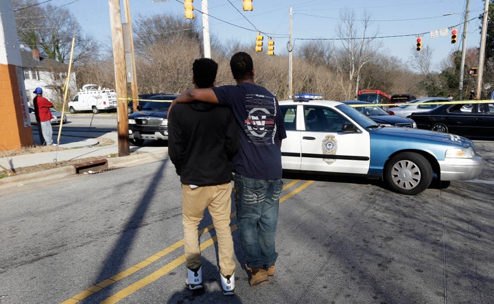 Bystanders walk near the scene a fatal shooting in Raleigh, N.C., Monday, Feb. 29, 2016. Authorities say that a police officer shot and killed a man while trying to make an arrest for a felony drug charge.