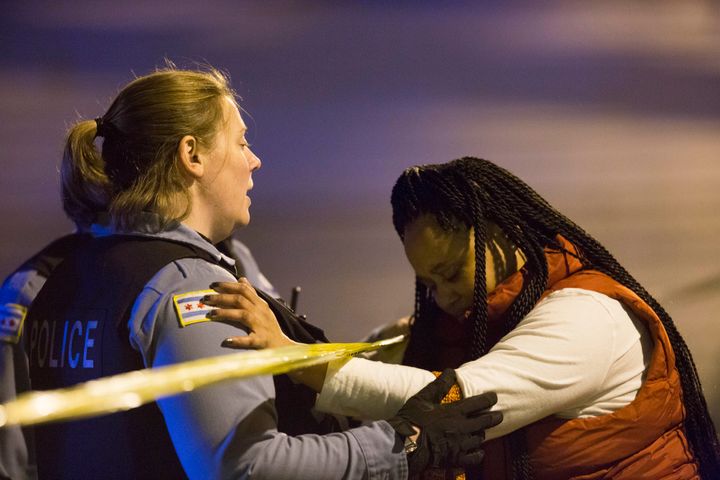 A member of the Chicago Police Department talks with Felicia Humphries at the scene where her son was shot and killed near the intersection of South Kilbourn Avenue and West Adams Street, Oct. 25, 2015, in Chicago.