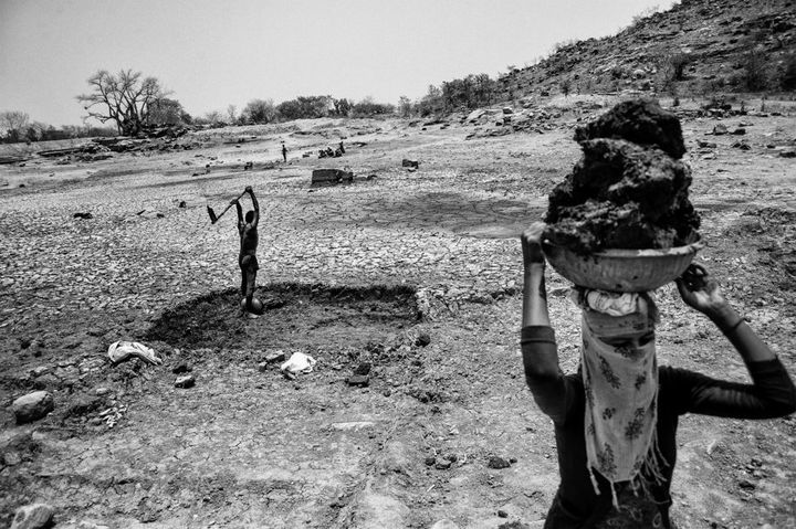 In the sweltering heat in Bundelkhand, a man and his wife remove silt from the bottom of a dried-out pond.
