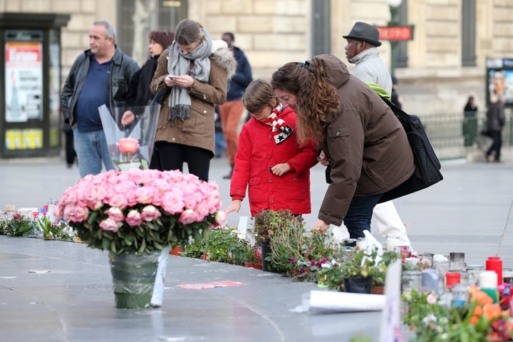 Pink flowers are left as people gather at Republique Square near tributes on Jan. 13, 2016, in Paris, France.