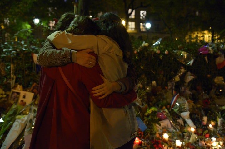 People hug in front of a memorial set-up near the Bataclan theatre in Paris.