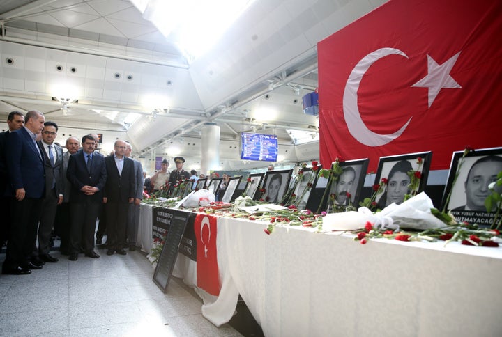 Turkey's President Recep Tayyip Erdogan, left, visits Ataturk Airport in Istanbul on Saturday, where photographs of last week's attack victims are displayed.