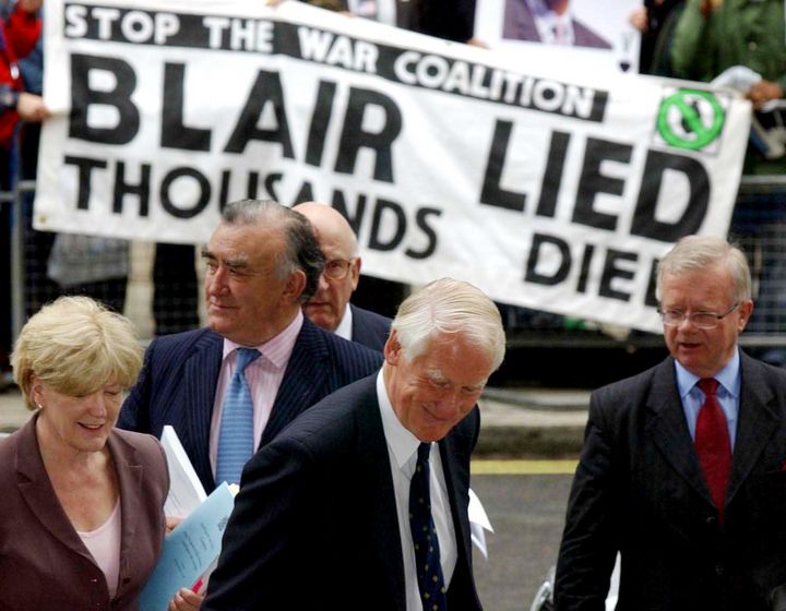 Lord Butler, centre, and his team, from left, Ann Taylor, Michael Mates, Lord Inge and Sir John Chilcott, pass protestors, as they arrive for a news conference in Westminster, London, on Thursday.