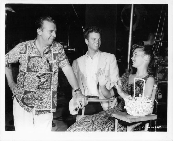 Dick Powell talks with Russ Tamblyn and Debbie Reynolds during a break from shooting the film "The Enemy Below," 1957.