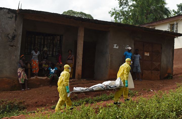 Health workers from Sierra Leone's Red Cross Society Burial Team 7 carry a corpse in Freetown on November 12, 2014.