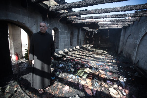 A priest inspects the damage at a room located on the complex of the Church of the Multiplication at Tabgha, on the shores on