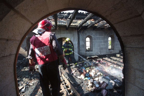 Firemen spray water on debris at a room located on the complex of the Church of the Multiplication at Tabgha, on the shores o