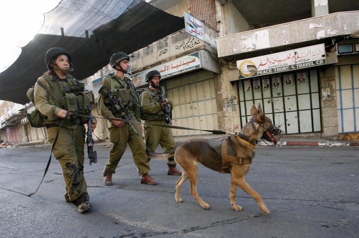 Israeli soldier patrols an empty street following the implementation of a curfew in Hebron, West Bank, in July 2009.