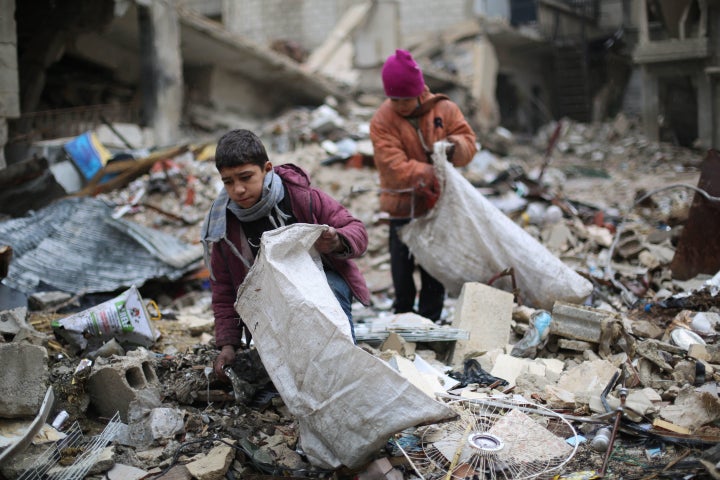 Syrian youths collect wood from rubble to be used for heating and cooking on Dec. 27 in Damascus, where residents have g