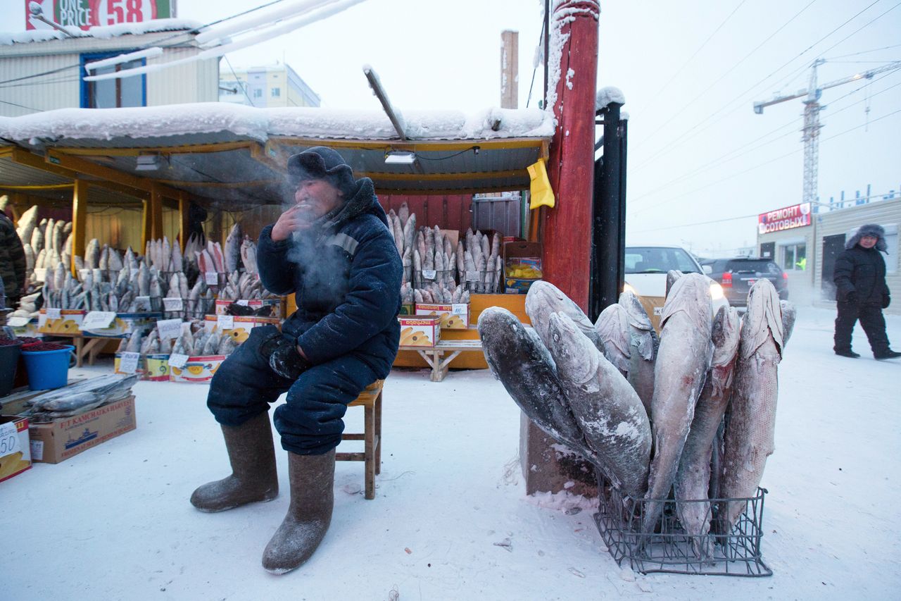 A food vendor sits beside a basket of frozen fish in the Krestyansky open air market in Yakutsk, Russia, on Feb. 17.